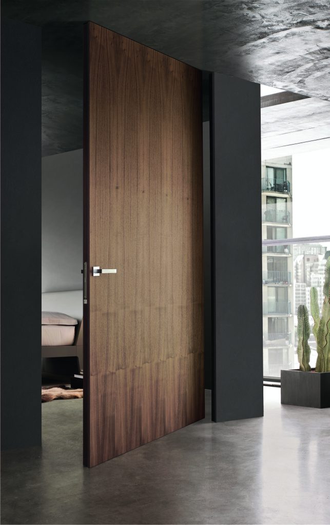 Wooden frameless walnut pivot door in a modern interior 