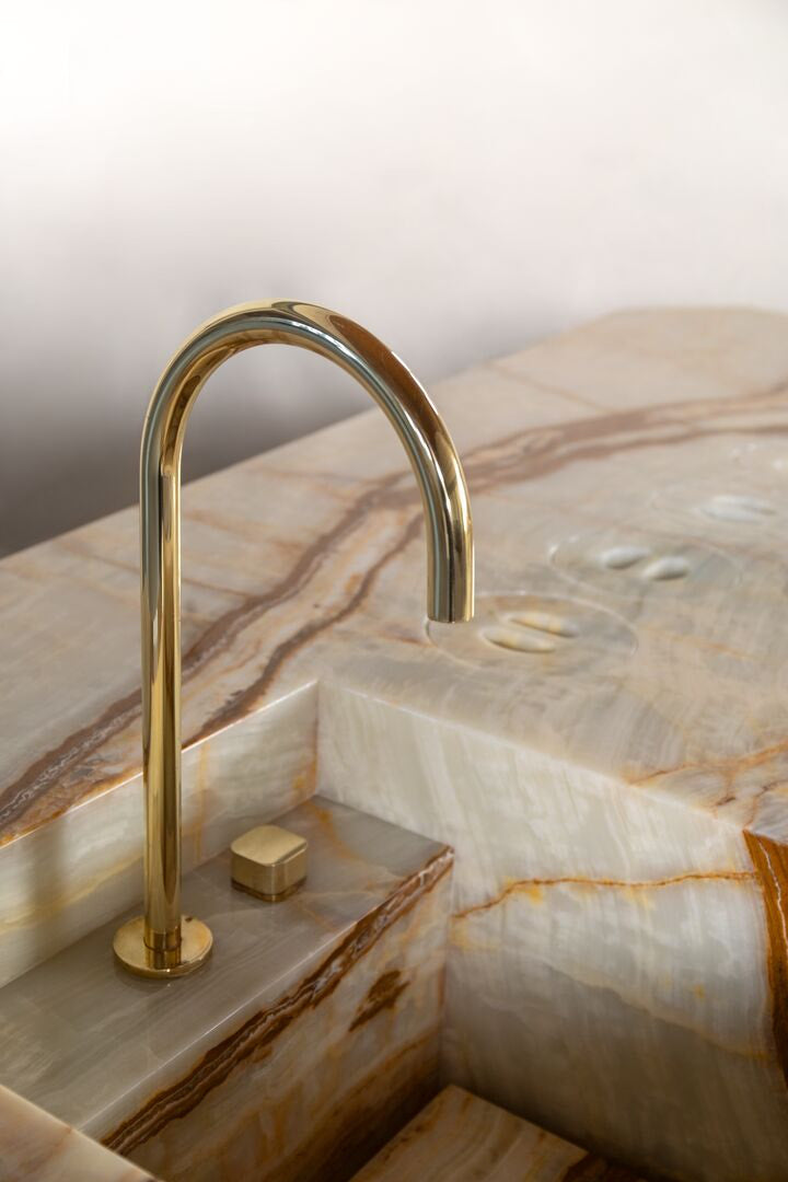 Gold faucet on a marble countertop with solid surface sink 