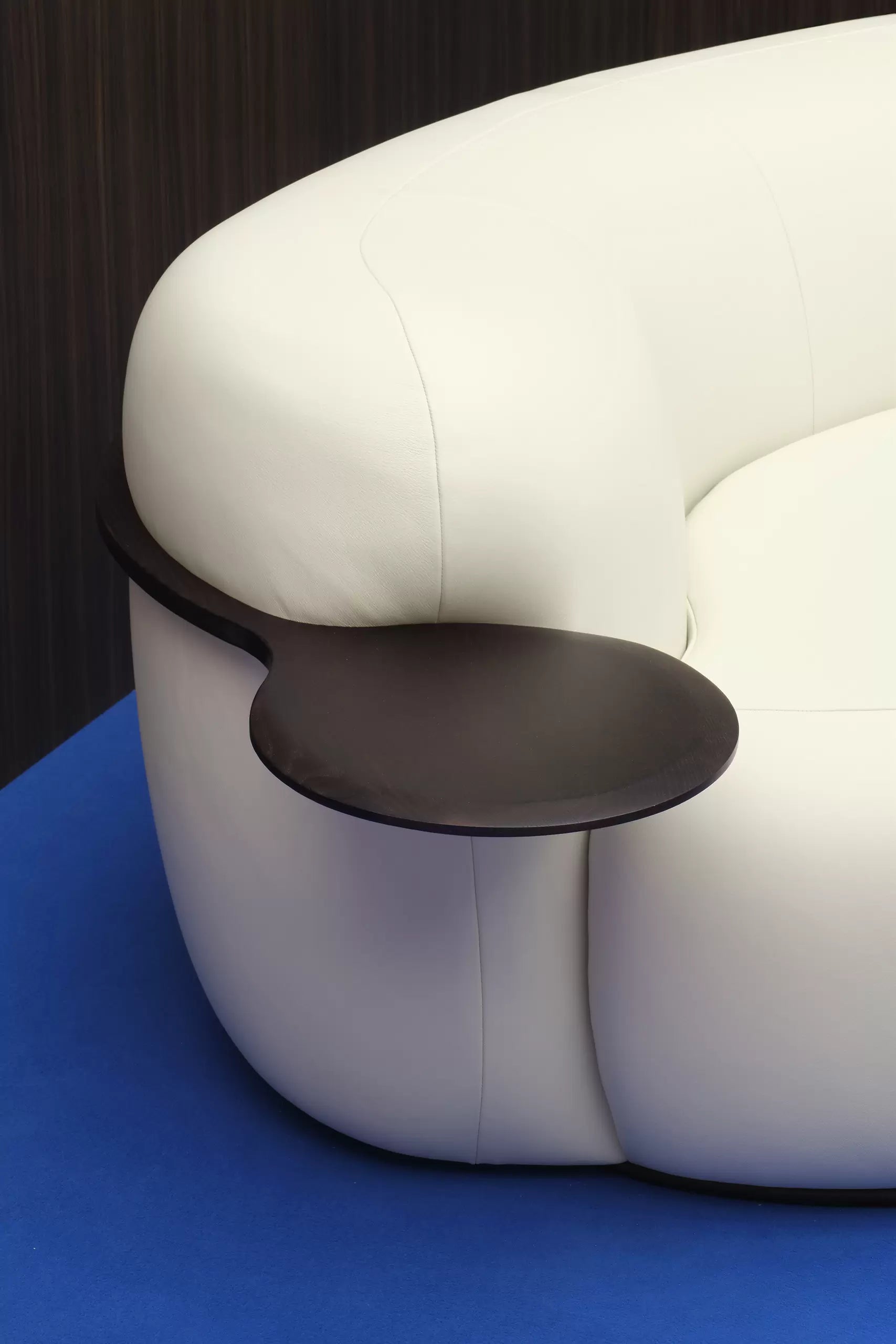 Modern white curved sofa with a dark wood side table