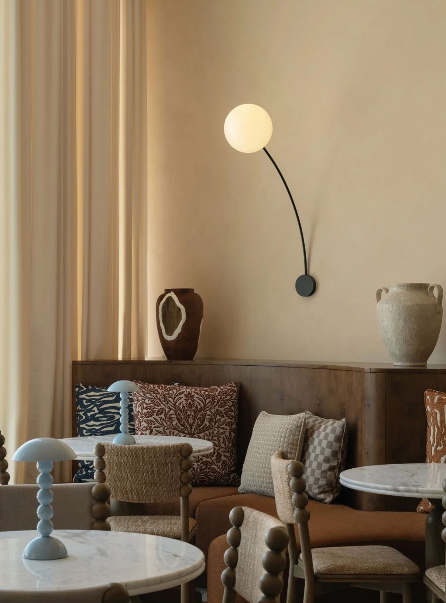 Cozy interior with a wall lamp, vases, and cushioned chairs.