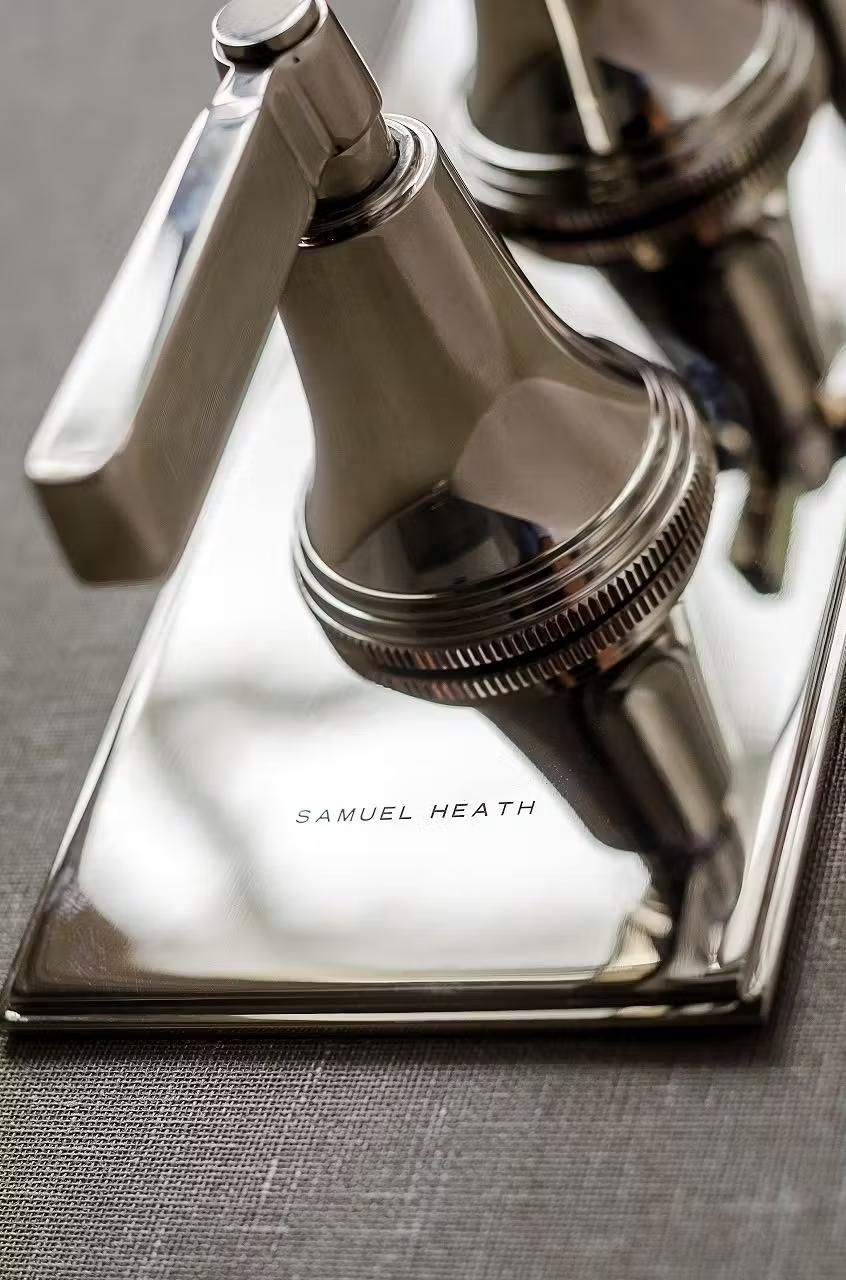 Chrome bathroom faucet with 'Samuel Heath' branding on a reflective surface.