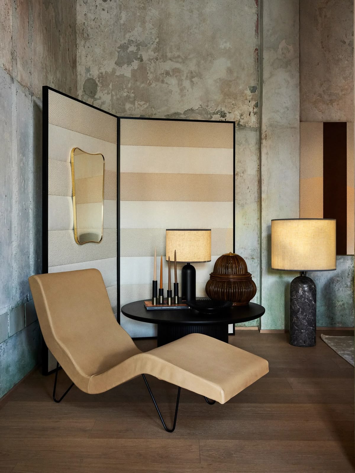 Modern interior with beige lounge chair, lamp, and decorative items against a textured wall.