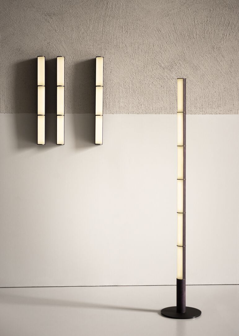 Modern wall sconces and floor lamp in dark bronze against a neutral wall.