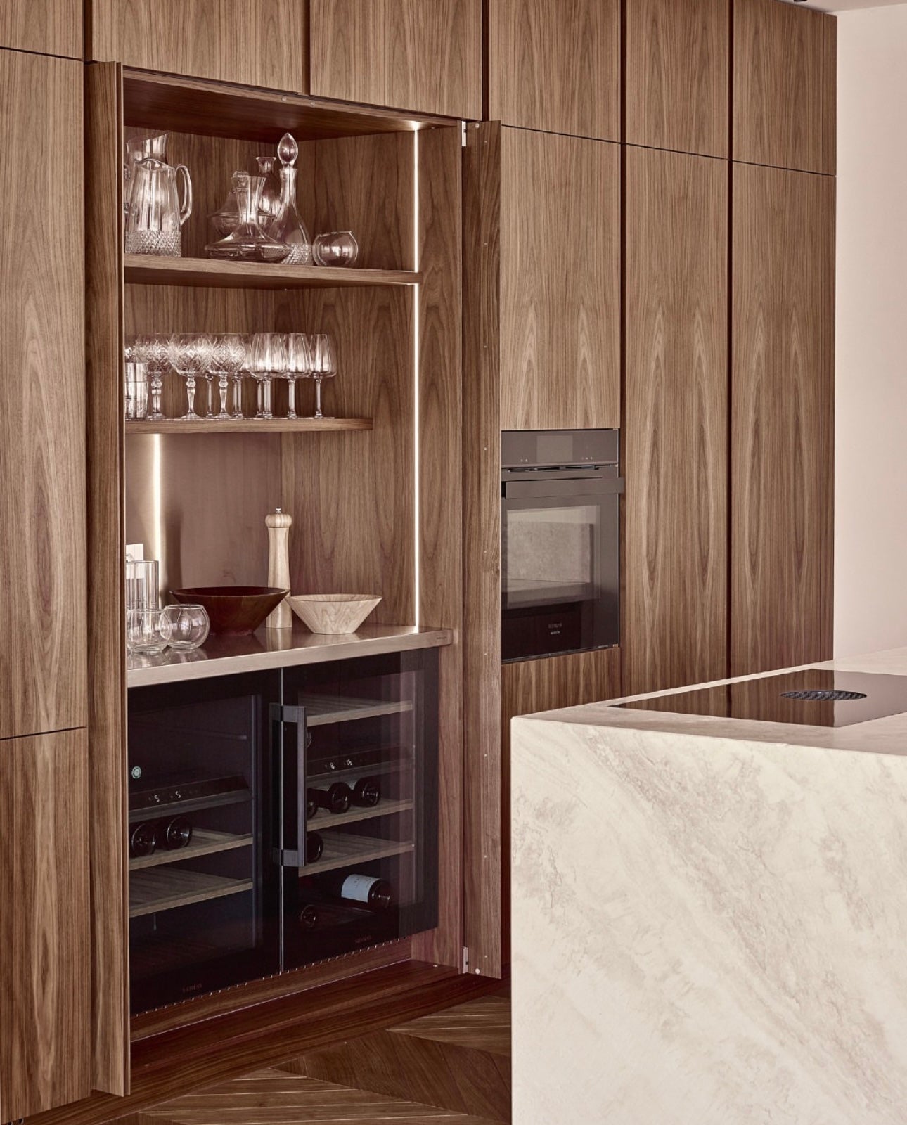 Wooden kitchen cabinetry with a bar area and seamless slide and hide pivot concealed pocket doors