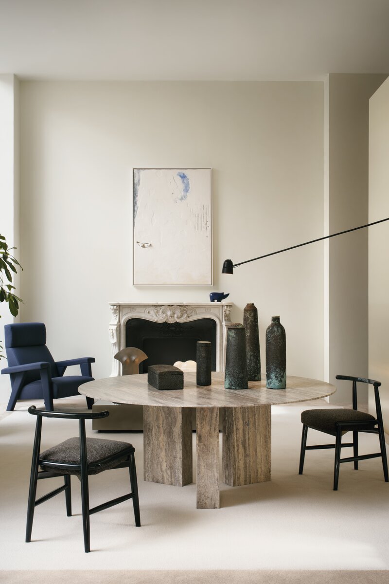 Modernist living room with a marble table, chairs, and abstract art on the wall.