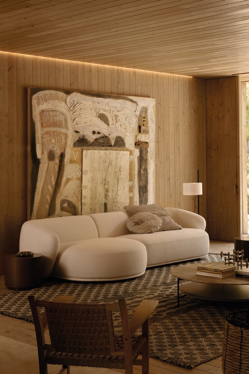 Modernist minimalist living room with a large abstract painting on the wall, a beige sofa, and a wooden chair.