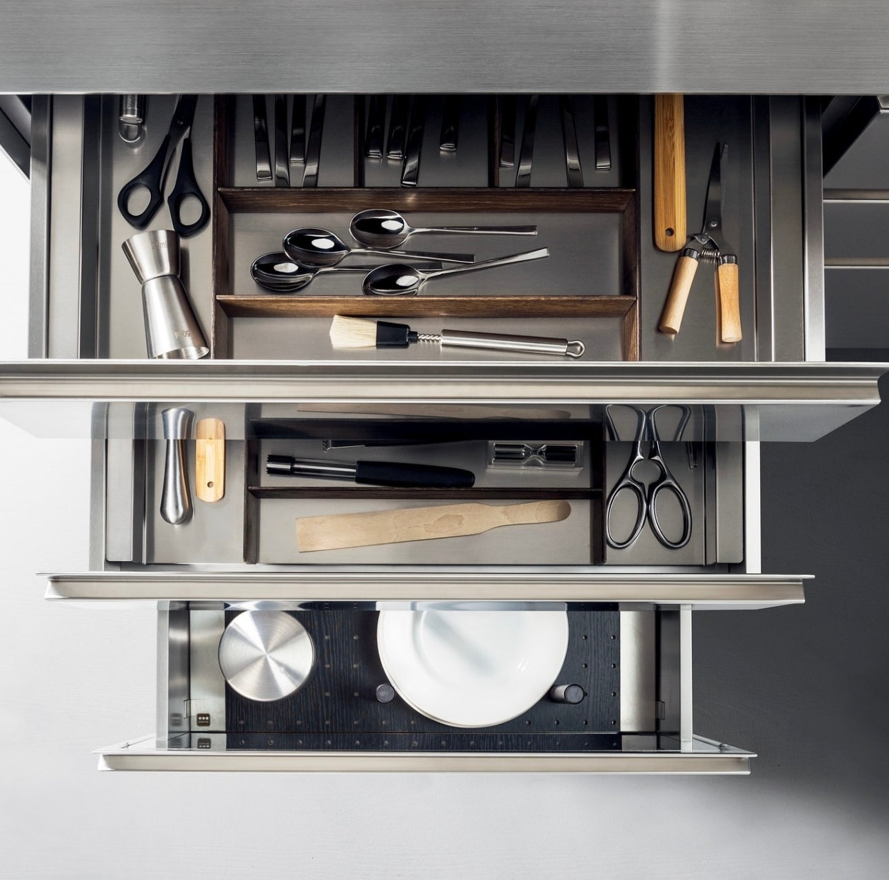 Open kitchen drawer with various utensils including knives, scissors, and measuring spoons.
