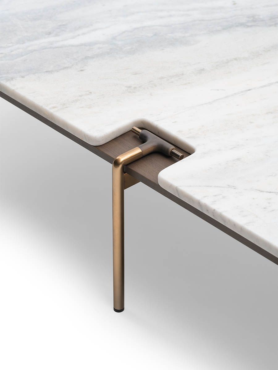 Close-up of a marble table with a bronze leg on a light gray background