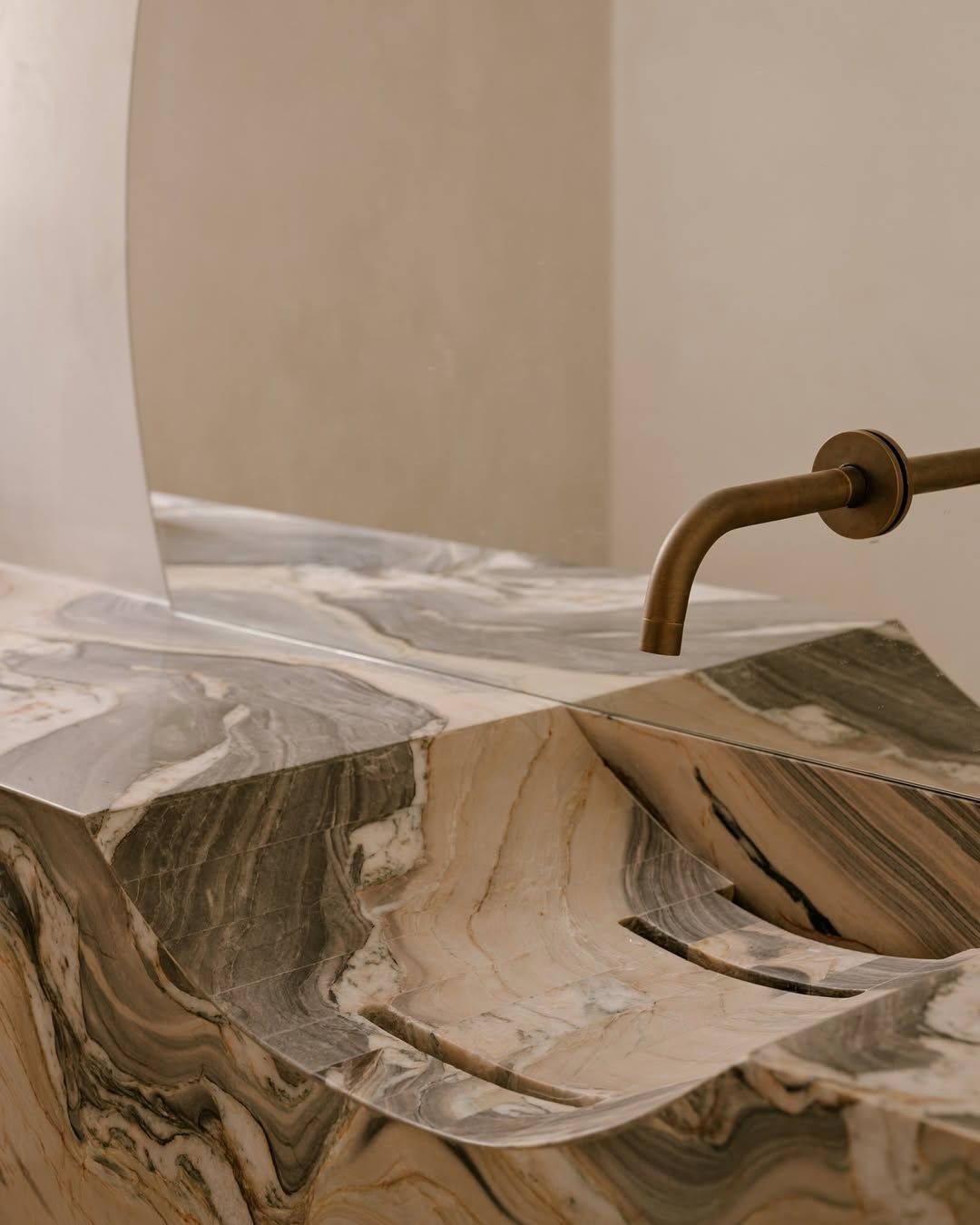 Modern marble curved sink with wall mounted bronze tap