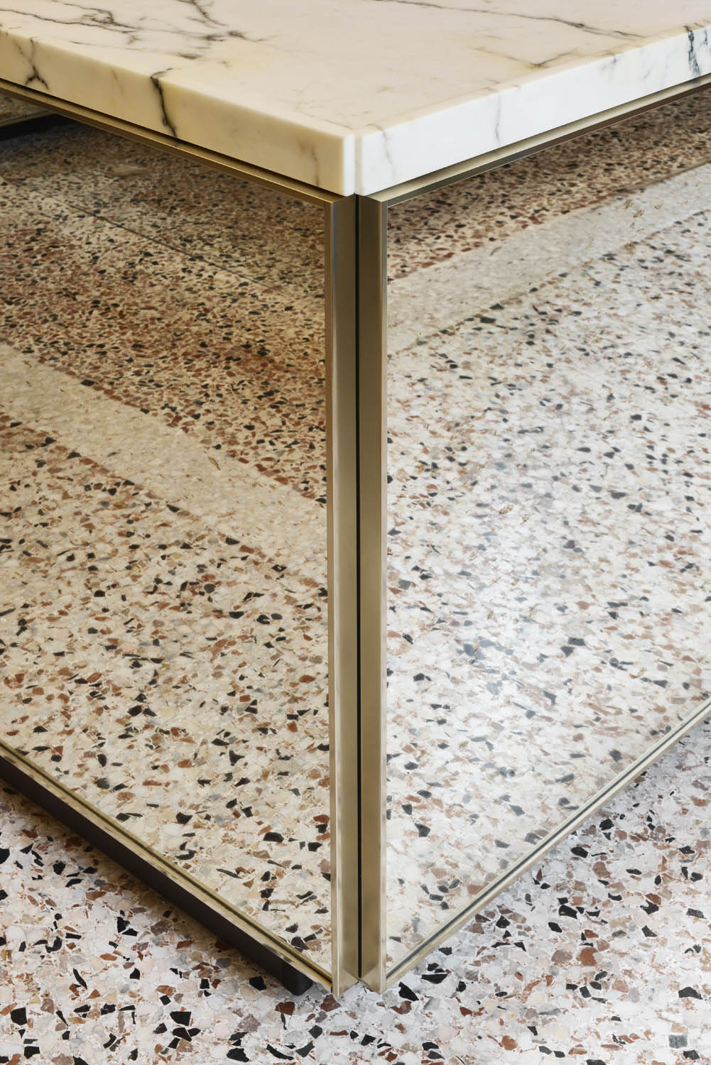 Close-up of a corner where a marble countertop meets a terrazzo floor.